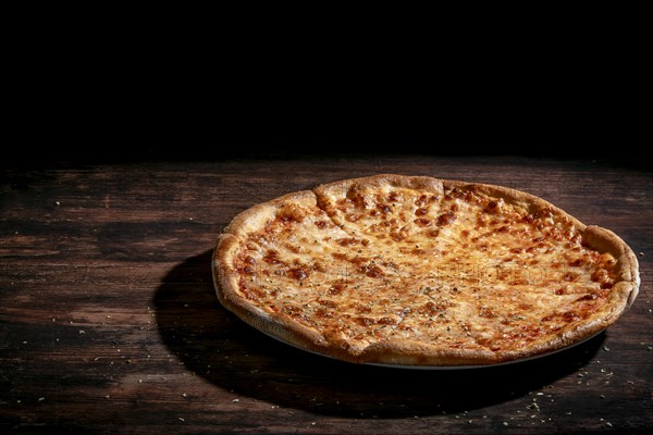 A Margherita pizza against a dark background on a wooden table