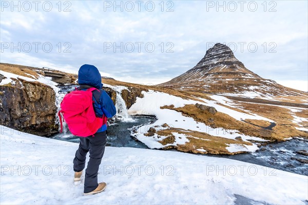 Adventurous photographer woman in winter in Iceland photographing in frozen Kirkjufell sunrise