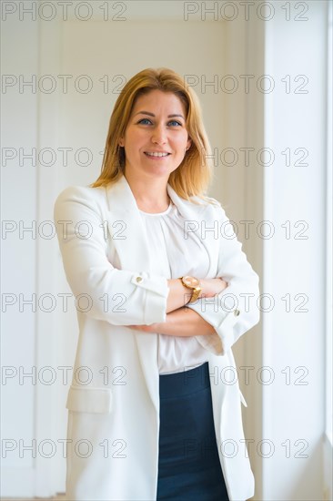 Vertical portrait of a proud female estate agent standing with arms crossed in the office