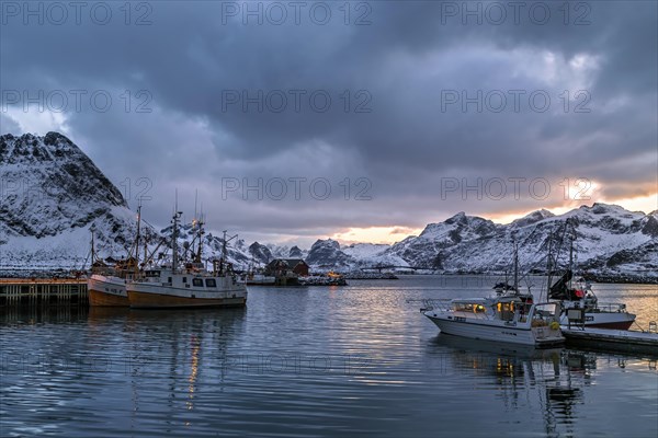 Evening at a tranquil harbor with fishing boats and snow-covered mountains in the background, Lofoten