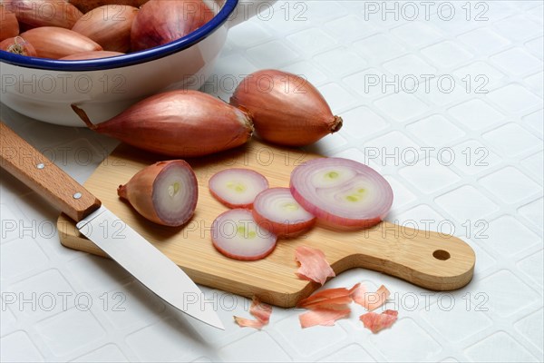 Sliced shallots on a wooden board with a knife, Allium cepa