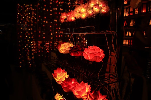 Illuminated lotus flower lamps on a rack at a night street market creating a warm, festive ambiance. Chiang mai, Thailand, Asia