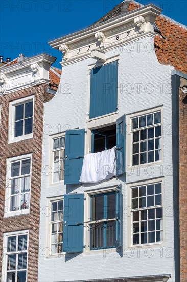 Historic house with open blue shutters and hanging white linen, Middelburg, Zeeland, Netherlands