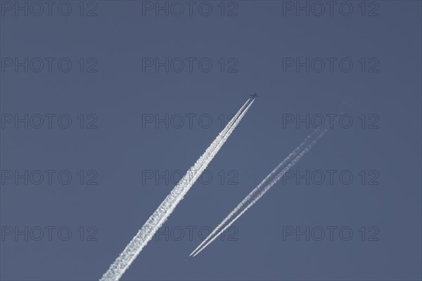 Two jet aircraft passing each other in flight with a contrail or vapour trail behind in the sky, England, United Kingdom, Europe