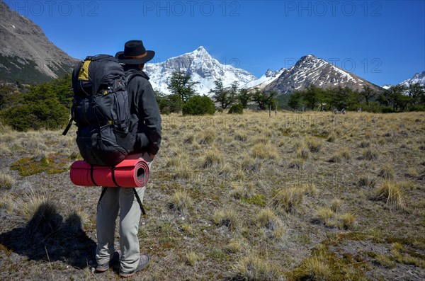 Hiker with a heavy rucksack in front of the snow-covered summit of Monte San Lorenzo, Perito Moreno National Park, Patagonia, Argentina, South America