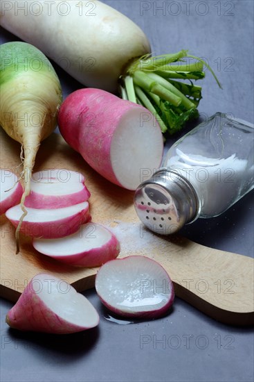 Various radishes on a wooden board, cut up and sliced