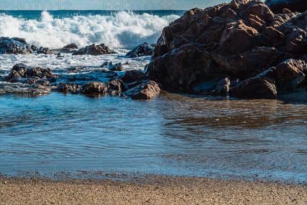 Crashing waves on rocky coastline with clear blue sky overhead, in South Korea