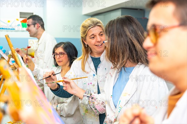 Art painting class of mental disabled students using brushes to paint on canvas