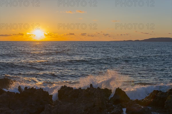 Sunset over the sea with waves breaking on rocks under a partly cloudy sky, Finikounda, Pylos-Nestor, Messinia, Peloponnese, Greece, Europe