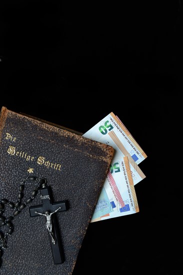 Bible, crucifix and banknotes, church and money, church tax