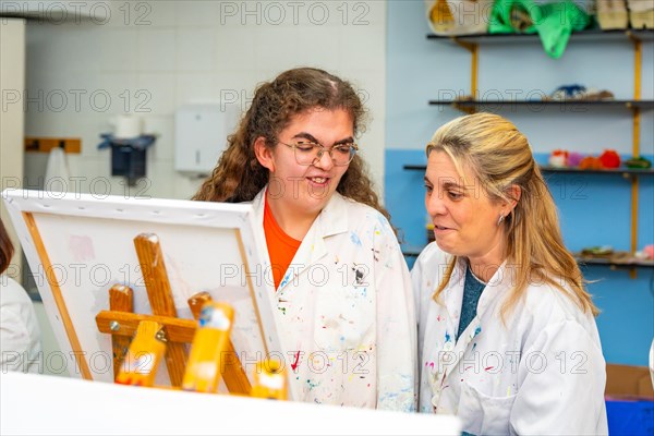 Disabled woman and teacher facing a canvas in a painting class