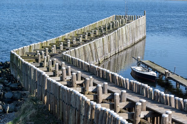 Wooden piles in the water form a jetty next to a boat at a quiet harbour, Veere, Zeeland, Netherlands