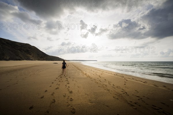 Young woman walking on the beach, emotion, rock, distance, cloudy, cloudy, mood, atmosphere, alone, lonely, empty, summer, summer holiday, holiday happiness, walk, sandy beach, tracks, footprints, active, walking, tourism, travel, symbolic, symbol, beach holiday, freedom, feeling of freedom, beach holiday, Algarve, Portugal, Europe