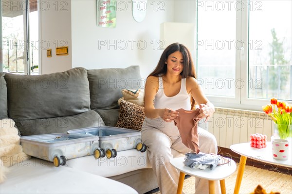 Horizontal photo with copy space of a pregnant woman preparing bag for the hospital sitting relaxed at home
