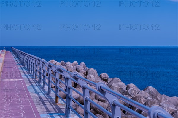 Sea wall and path bathed in blue twilight hues with calm sea waters stretching into the distance, in South Korea
