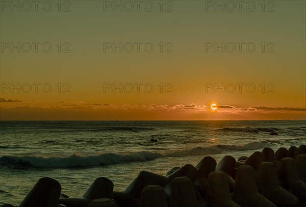 Warm sunrise over the ocean with waves crashing against tetrapods, in South Korea