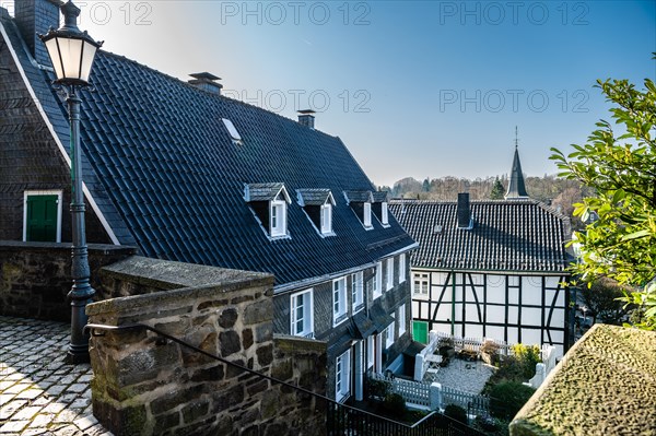 View of an alley with historic half-timbered houses and a church spire in the background, Graefrath, Solingen, Bergisches Land, North Rhine-Westphalia