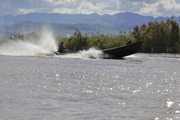 Fast boat travelling at high speed on a river and creating splashing water, Inle Lake, Myanmar, Asia