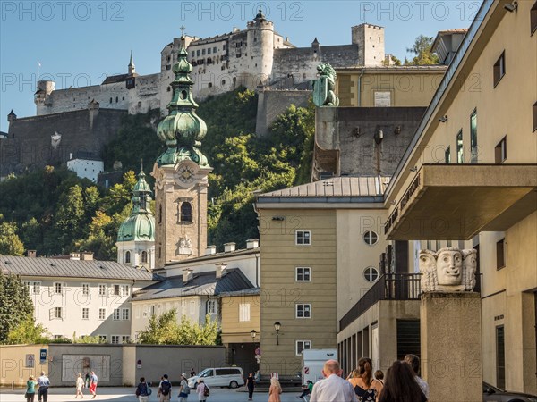 View of a historic castle above the city with a clear sky and people in the foreground Salzburg Austria