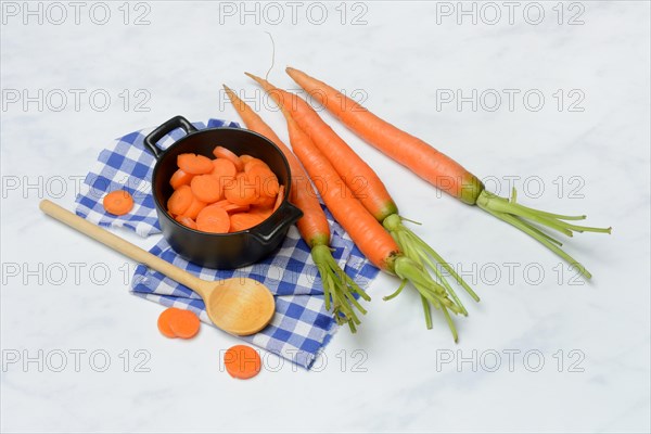 Carrot slices in pots and wooden spoon, carrot (Daucus carota)