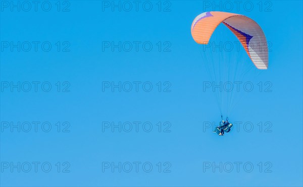 Paraglider in flight against a serene blue sky, exemplifying extreme sports, in South Korea