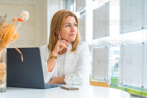 Beauty mature female financial advisor looking through the window from the office