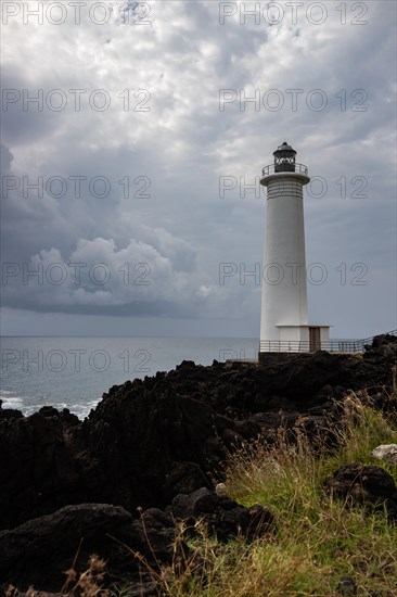 White lighthouse on a steep coast. Dramatic clouds with a view of the sea, pure Caribbean at Le Phare du Vieux-Fort, on Guadeloupe, French Antilles, France, Europe