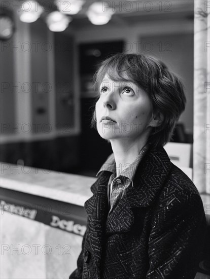 Black and white image of a contemplative woman gazing upwards, standing by a marble counter indoors, AI generated