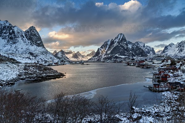 Winter view of a fjord surrounded by snow-capped mountains and a small village, Lofoten