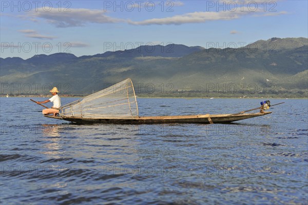 Fishermen on a boat in sunny weather, picturesque mountain scenery in the background, Inle Lake, Myanmar, Asia