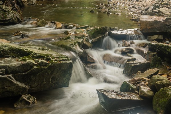 Closeup of water from small mountain stream cascading over rocks and boulders in South Korea