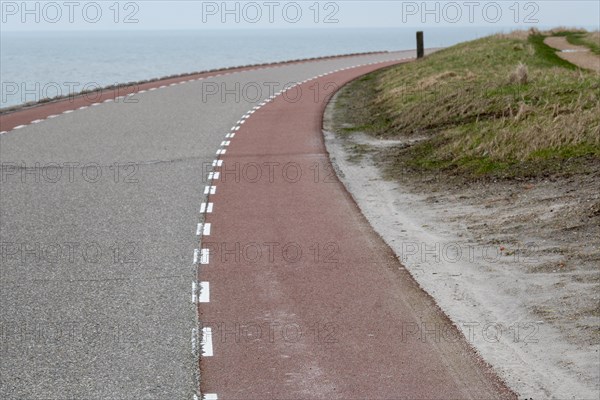 A winding road and a cycle path next to the sea under a cloudy sky