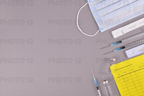 Virus antigen test, vaccine passport, medical face masks, vaccine vials with syringes on gray background with copy space