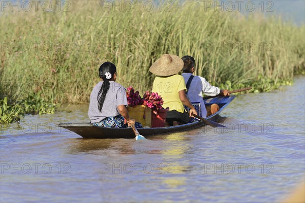 Three people paddling together in a narrow canoe, Inle Lake, Myanmar, Asia