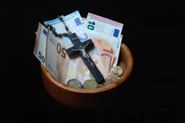 Crucifix and banknotes in a bowl, church and money, church tax