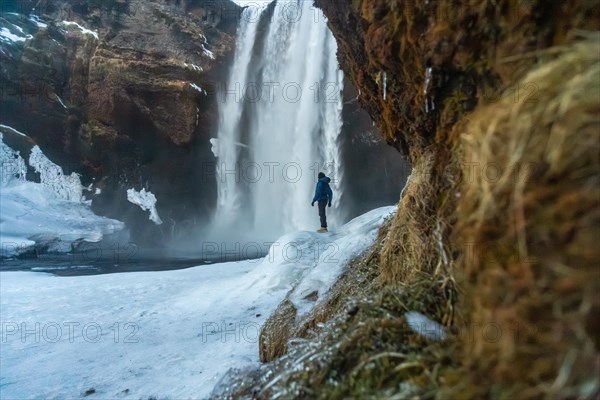 Silhouette of woman in winter in Iceland under the Skogafoss waterfall with temperatures of 20 below zero. With the ground frozen with ice