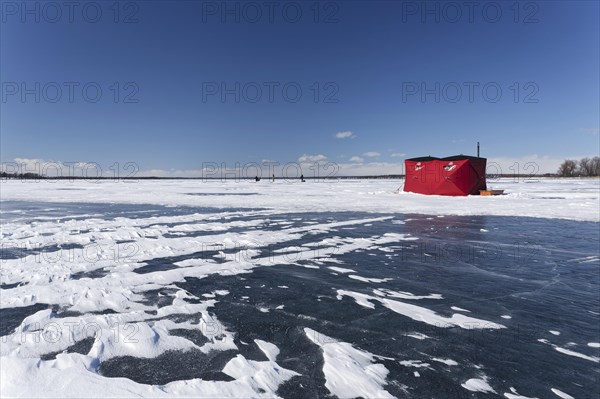 Winter, red fishing hut with snow drifts on a frozen riverscape, Saint Lawrence River, Province of Quebec, Canada, North America