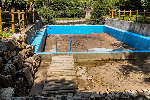 Deserted sandbox surrounded by a blue fence with a small wooden bridge, in South Korea