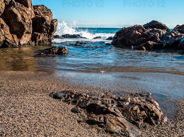 Rocky shoreline with whitecaps on the sea under bright daylight, in South Korea