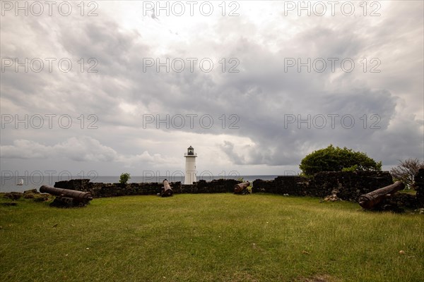 White lighthouse on a steep coast. Dramatic clouds with a view of the sea, pure Caribbean at Le Phare du Vieux-Fort, on Guadeloupe, French Antilles, France, Europe