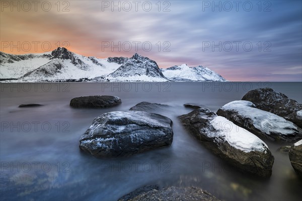 Rocky coast at the fjord with snow-covered mountains at sunset, Steinfjorden, Tungeneset, Husfjellet, Senja Island, Norway, Europe