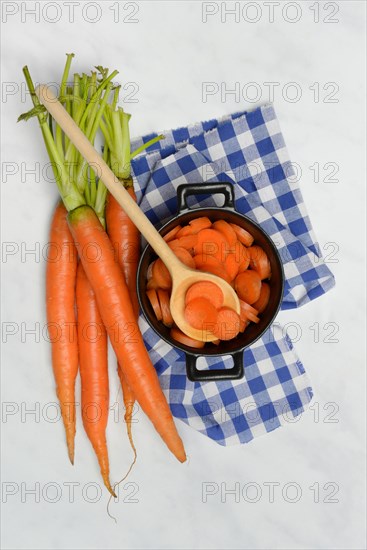 Carrot slices in pots and wooden spoon, carrot (Daucus carota)