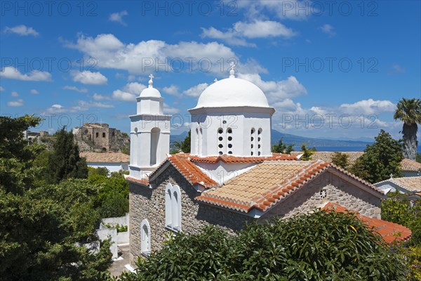 Bright church with white domes, surrounded by green trees and red roofs, viewpoint on the left, view of the Holy Monastery of Timi Prodromos, Byzantine fortress, nunnery, Koroni, Pylos-Nestor, Messinia, Peloponnese, Greece, Europe
