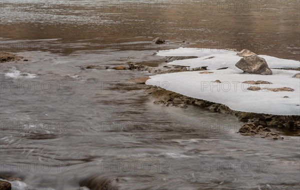 Serene winter river with small snow islands amidst a stone riverbed, in South Korea