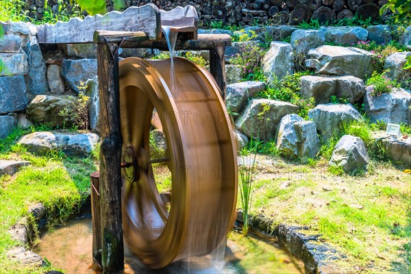 Spinning waterwheel by a stone wall demonstrates traditional water harnessing methods, in South Korea