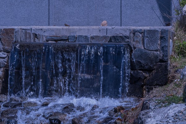 Water flows over a man-made stone waterfall structure, in South Korea