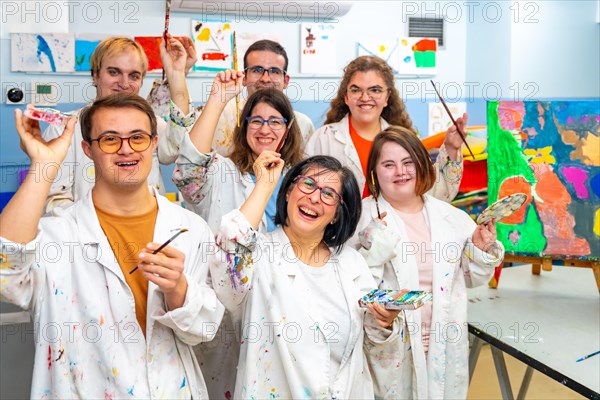 Portrait of a group of happy disabled people with dirty coats in a painting class