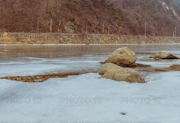 Peaceful frozen river scene with rocks during a calm winter dusk, in South Korea