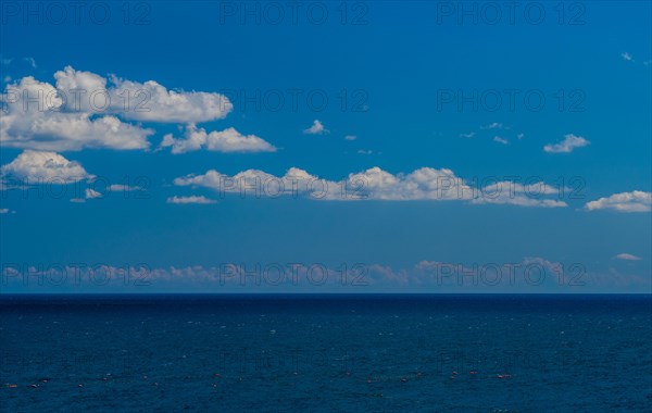 Expansive view of the ocean beneath a clear blue sky with fluffy clouds, in South Korea