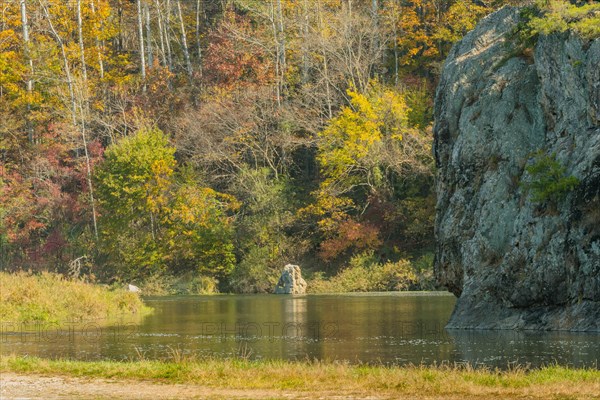 Tranquil view of a rock formation with trees in autumn colors reflecting in a lake, in South Korea